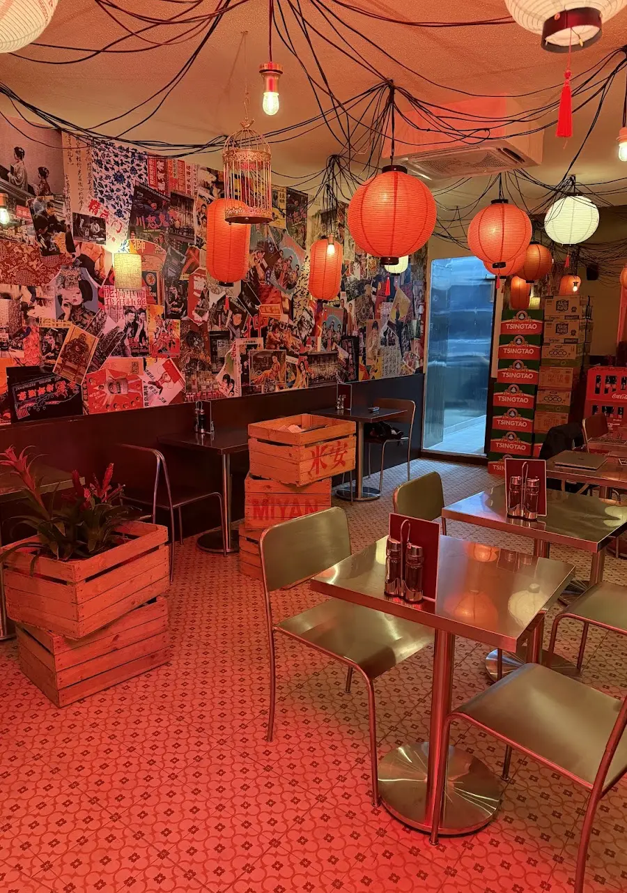 Salle de MIYAN avec lanternes rouges, murs en affiches et caisses en bois